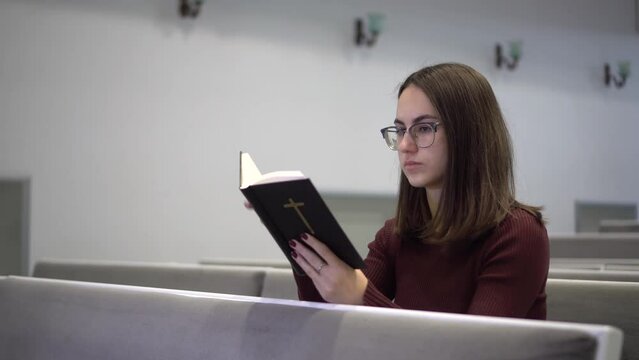 A young woman reads the Bible while sitting