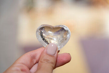 holding a crystal  clear quartz heart  between fingers