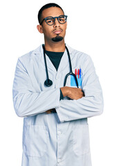 Young african american man wearing doctor uniform and stethoscope skeptic and nervous, disapproving expression on face with crossed arms. negative person.