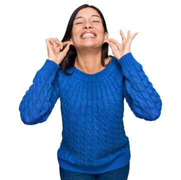 Young hispanic woman wearing casual clothes smiling pulling ears with fingers, funny gesture. audition problem