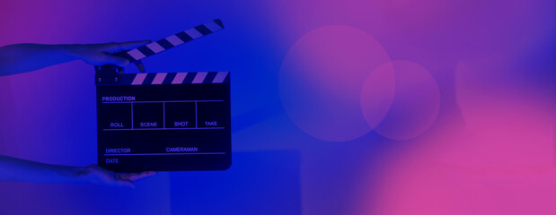 Fototapeta na wymiar Hand holds empty film making clapperboard on color background in studio