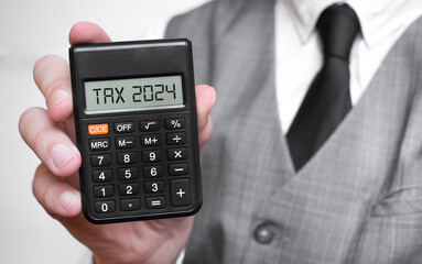 tax 2024 word text inscription on calculator in a male hand of a businessman in white shirt - obrazy, fototapety, plakaty