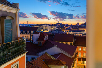 A colorful dramatic sunset sky over the cityscape and Ponte 25 de Abril bridge seen from the hillside medieval Alfama district in Lisbon Portugal. - Powered by Adobe
