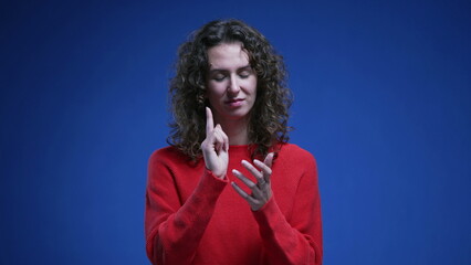 Young woman applauding viewer and pointing finger acknowledging successful achievement. 20s female person congratulating standing on blue backdrop