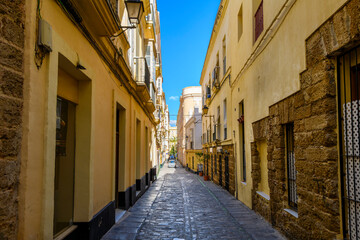 Fototapeta na wymiar A narrow cobblestone alley in the historic medieval old town of the ancient Spanish city of Cádiz, Spain.