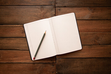 Open notebook and pencil on a rustic wooden board