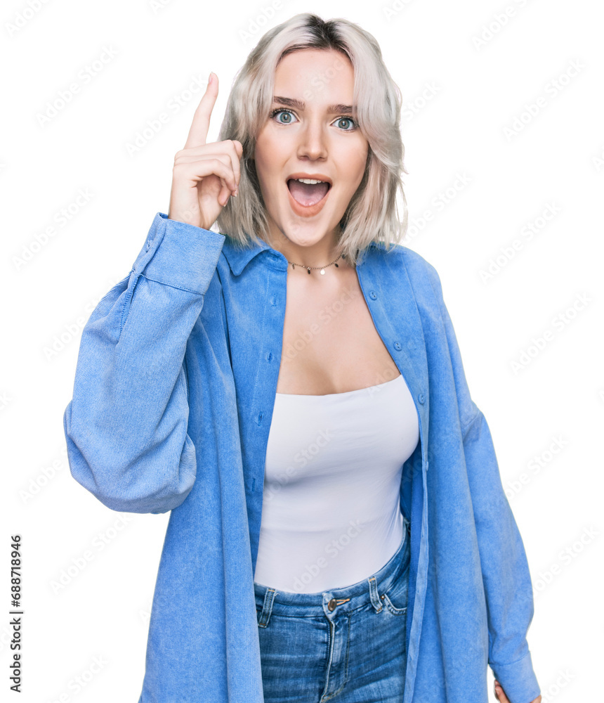 Sticker Young blonde girl wearing casual clothes pointing finger up with successful idea. exited and happy. number one.