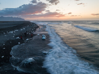 Sunrise at the Diamond Beach, Fellsfjara black sand beach, Vatnajökull Glacier National Park, Iceland. Photographers standing in surf with tripods.
