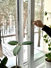 Male person hand opening plastic window for ventilation in winter time