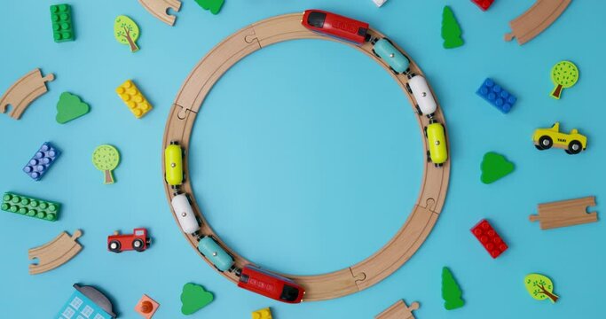 Two toy wooden trains with cars riding on circular railroad on blue background