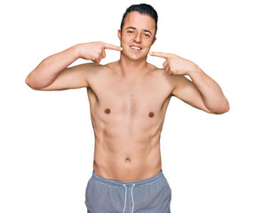 Fototapeta premium Handsome young man wearing swimwear shirtless smiling cheerful showing and pointing with fingers teeth and mouth. dental health concept.