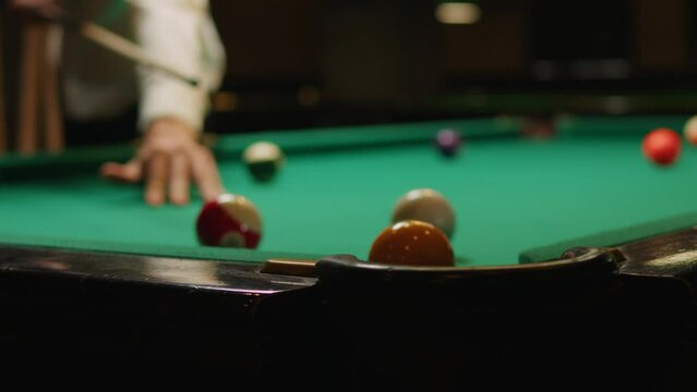 Young man playing American billiard poule close-up. Colorful balls on green billiards table .Billiard balls with numbers on a pool table. Billiards team sport.