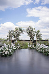 Wedding ceremony. Very beautiful and stylish wedding arch, decorated with various fresh flowers, standing in the garden.