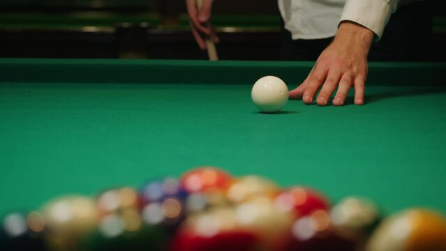 Young man breaking colorful pool balls with cue on green billiards table for start to play. American pool, poule game. Billiard balls with numbers on a pool table. Billiards team sport.