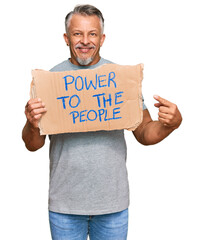 Middle age grey-haired man holding power to the people banner smiling happy pointing with hand and finger