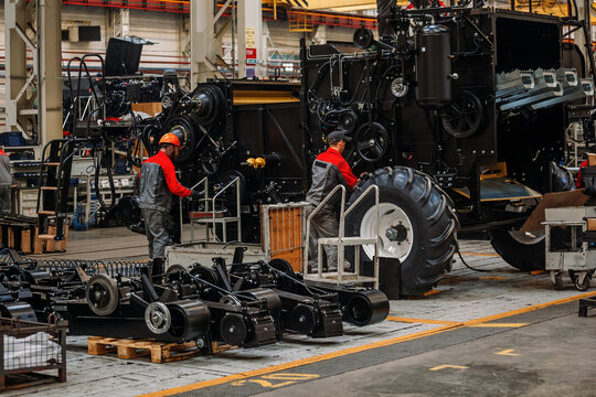 Industrial workers assembles agricultural harvester in workshop