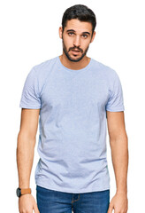 Young hispanic man wearing casual clothes in shock face, looking skeptical and sarcastic, surprised with open mouth