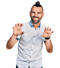 Hispanic man with ponytail wearing casual white shirt smiling funny doing claw gesture as cat,...