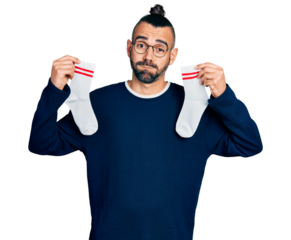 Hispanic man with ponytail holding socks puffing cheeks with funny face. mouth inflated with air, catching air.