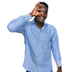 Fototapeta premium Handsome business black man wearing casual striped t shirt smiling happy doing ok sign with hand on eye looking through fingers