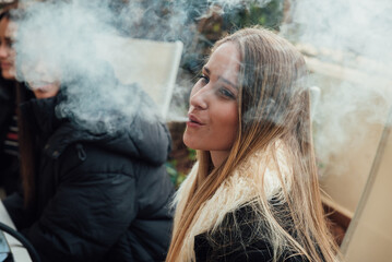 Young woman in warm clothes smoking