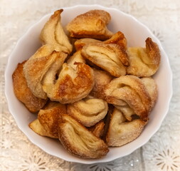 Puff pastry buns in close-up in a white glass plate on a light tablecloth background