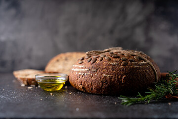 Sliced sourdough bread from whole grain flour and pumpkin seeds on a grid, olive oil and black olive on a rustic wooden table. Artisan bread.