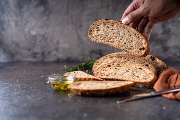 Sliced sourdough bread from whole grain flour and pumpkin seeds on a grid, olive oil and black...