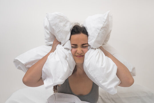 Sleep eludes her as she grips pillows to her ears, combating a headache and insomnia caused by inconsiderate neighbors. 