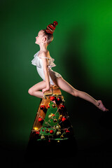 A girl gymnast in a white gymnastic leotard does an acrobatic stretching exercise. Nearby is a...