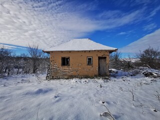 Old abandoned beautiful hut. Cottage covered with the first snow. Winter landscape