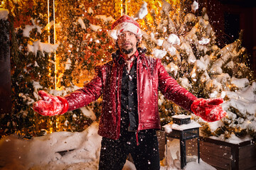Man dressed as Santa Claus throws up snow on a street decorated with garlands. New Year and Christmas concept.