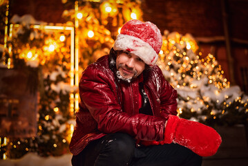 Man dressed as Santa Claus poses on a street decorated with garlands. New Year and Christmas concept
