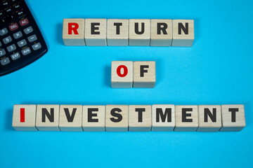 Return of investment. Concept of good ROI and making money.
Cube wooden blocks with  a calculator and text 