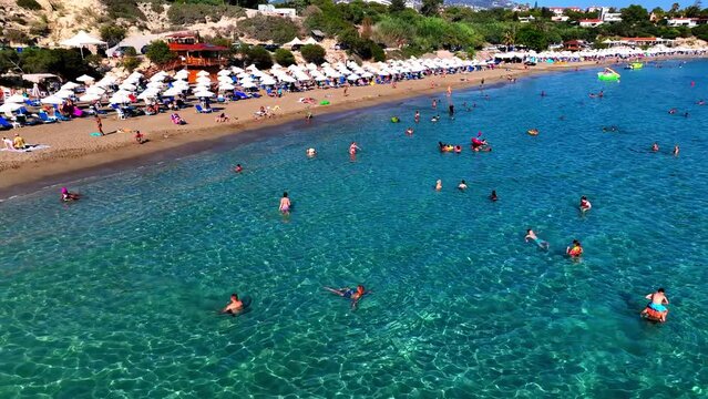 Aerial: Drone Panning Forward Shot Of Men And Women Exploring Beach By Cliff On Sunny Day - Paphos, Cyprus