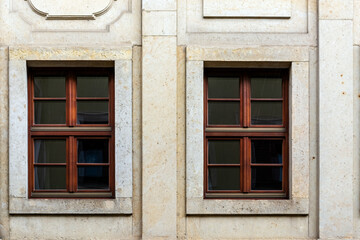 Fototapeta na wymiar Two rectangular windows with a brown frame on the background of a beige tile wall. From the Windows of the world series.