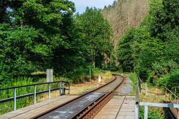 Railway stop on a single-track railway in the forest on a bright sunny summer day.