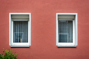 Fototapeta na wymiar Two rectangular windows with a white frame against a pink plastered wall. From the Windows of the world series.