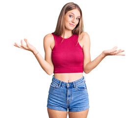 Young beautiful blonde woman wearing elegant summer shirt clueless and confused expression with...