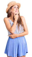 Young beautiful blonde woman wearing summer hat thinking worried about a question, concerned and nervous with hand on chin