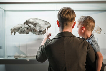 Woman holding her little son in front of the showcase with animal skeleton and skull during a...