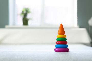 Multi-colored plastic pyramid toy in child playing room. Happy childhood concept