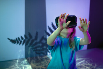 Female child using new technologies, having fun wearing virtual reality goggles in the VR room of natural history museum.