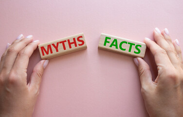 Facts or Myths symbol. Concept word Facts or Myths on wooden blocks. Businessman hand. Beautiful pink background. Business and Facts or Myths concept. Copy space