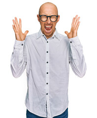 Bald man with beard wearing business shirt and glasses celebrating mad and crazy for success with...