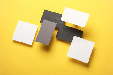 Composition of floating square memo papers and business cards on yellow background. Mockup....