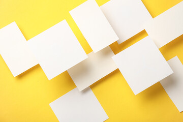 Composition of floating white square memo paper and business cards on yellow background. Mockup....