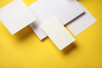 Composition of floating white square memo paper and cards on yellow background. Mockup. Business...