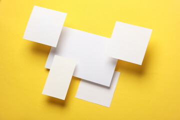 Composition of floating white square memo paper and cards on yellow background. Mockup. Business concept - obrazy, fototapety, plakaty
