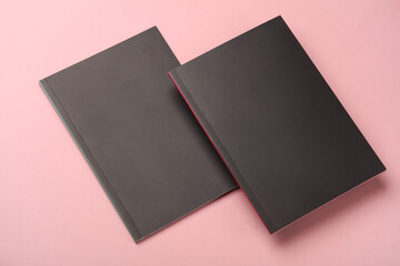 Two notebooks with black covers on a pink background